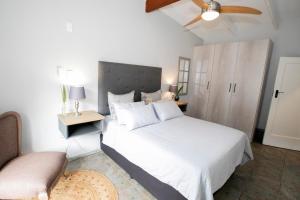 a bedroom with a white bed and a ceiling fan at Buchan's Corner Unit 2 in Hartbeespoort