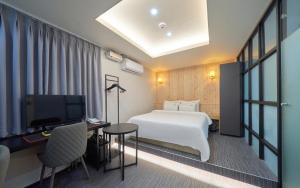 a hotel room with a bed and a desk and a tv at Hotel Haeseong in Changwon