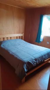 a bed in a room with a blue blanket on it at Cabaña coñico in Coñico