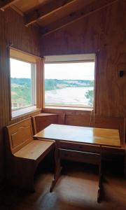 a dining room with a table and two windows at Cabaña coñico in Coñico