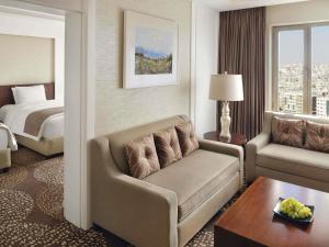 een hotelkamer met een bank en een bed bij Mövenpick Hotel Amman in Amman