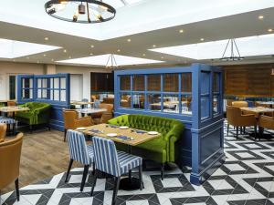 a restaurant with a green couch and tables and chairs at Mercure Oxford Hawkwell House Hotel in Oxford