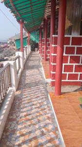 een wandelpad dat naar een gebouw met rode pilaren leidt bij Sea View Cottages in Arambol