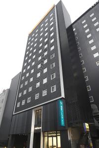 Un edificio alto y negro con un cartel. en Sotetsu Fresa Inn Ginza-Nanachome en Tokio