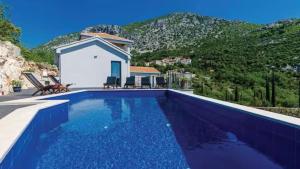 a swimming pool in front of a house with a mountain at Villa Bohemia by Villas Guide in Dubrovnik