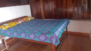 een klein bed in een kamer met houten wanden bij Sea View Cottages in Arambol