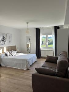 ein weißes Schlafzimmer mit einem Bett und einer Couch in der Unterkunft Apartagal-A Corredoira in Foz