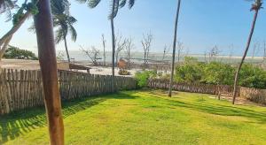 a yard with palm trees and a fence and the beach at Casa Bella Guriú in Guriú