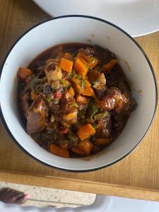 Eine Schüssel Eintopf mit Karotten und Fleisch auf einem Tisch in der Unterkunft Legit Motel in Kampala