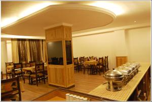 una sala da pranzo con tavoli e sedie e una grande stanza con un tavolo sidx sidx di Lords Residency a Manāli