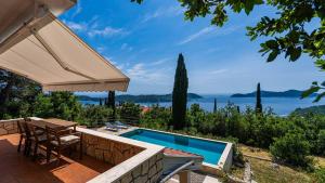 an outdoor patio with a pool and an umbrella at Grand view Orasac by Villas Guide in Dubrovnik