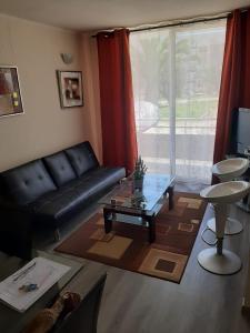 a living room with a black leather couch and a table at Galicia in La Serena