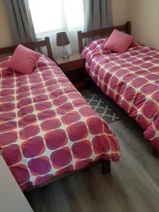two beds sitting next to each other in a bedroom at Galicia in La Serena +1 photo