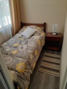 a bed with a pillow and a night stand next to a window at Galicia in La Serena