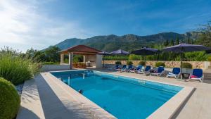 a swimming pool with chairs and umbrellas at Cypress Paradise by Villas Guide in Dubravka
