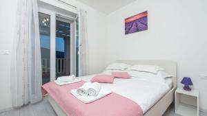 a white bedroom with pink and white towels on a bed at Cypress Paradise by Villas Guide in Dubravka +33 photos