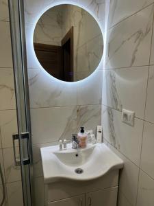 een badkamer met een witte wastafel en een spiegel bij Happy moments Studio Kraljevo in Kraljevo +3 foto's