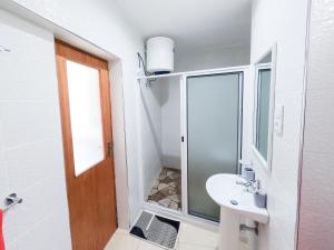une salle de bains blanche avec un lavabo et un miroir dans l'établissement Residencial Mãe Nona, à Ribeira Grande