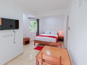 une chambre avec un lit, une table et une télévision dans l'établissement Residencial Mãe Nona, à Ribeira Grande