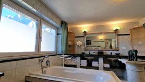 a bathroom with a large tub and a large window at Alpine Schmiede Chalet in Ehrwald +25 photos