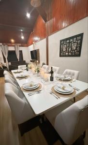 un lungo tavolo con sedie bianche e una tovaglia bianca di Casa Marrom dos Mellos, Campos do Jordão a Campos do Jordão