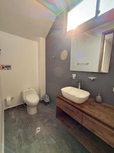 een badkamer met een toilet, een wastafel en een spiegel bij Casa boreales in Quimbaya