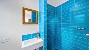 a blue tiled bathroom with a sink and a mirror at Beautiful high-set studio close to beach in Ocean Shores