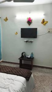 a bedroom with a bed and a tv on a wall at Le Green House Villa in Pondicherry