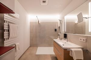 een witte badkamer met een wastafel en een douche bij Der Sonnenhof in Bad Wörishofen