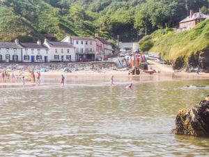 un gruppo di persone in piedi in acqua in una spiaggia di Dol Llan - Hw7569 a Llangrannog