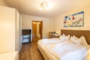 a bedroom with a large white bed and a desk at Hotel Austria Wildschönau & Wildschönau Premium Card in Niederau