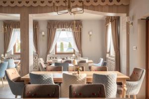 a dining room with tables and chairs and windows at Willa Jędruś in Murzasichle