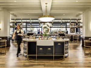 a woman walking through a restaurant with a bar at Fairmont Banff Springs in Banff