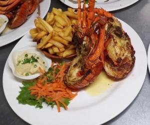 un piatto di cibo con un'aragosta e patatine fritte di Tropical Place a HUH