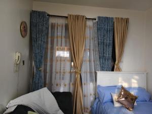 une chambre avec un lit et une fenêtre avec des rideaux dans l'établissement Flo Steve Stays, à Nairobi
