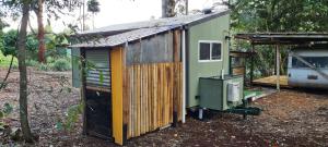 a small green and wooden house in the woods at Forest Gypsy Tiny Home in Barkers Vale +5 photos