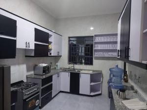 a kitchen with white and black cabinets and a stove at Mwisenix apartment in Kigali