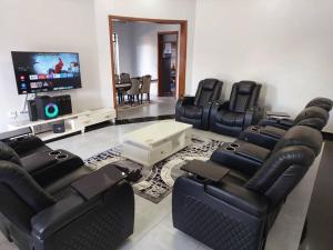a living room with black leather chairs and a flat screen tv at Mwisenix apartment in Kigali