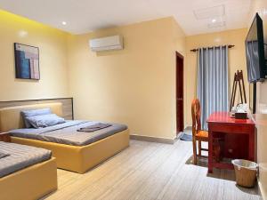 a bedroom with two beds and a desk and a computer at The Ray Hotel & Apartments in Phnom Penh
