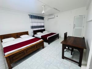 een slaapkamer met twee bedden en een tafel erin bij Vinola Hotel in Mannar +3 foto's