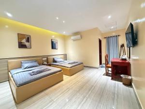 a bedroom with two beds and a desk and a television at The Ray Hotel & Apartments in Phnom Penh