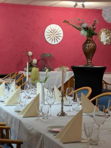 une table avec des nappes blanches et un mur rose dans l'établissement Hotel & Restaurant Mediterrane Küche, à Horn-Bad Meinberg