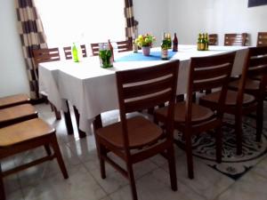 基加利ZEBRA CLASSIC b&b的一张桌子，配着木椅；还有一张白色桌子，上面放着瓶子。