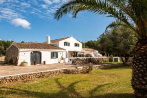 una casa bianca con una palma di fronte di Finca Biniparrell Vell a Sant Lluís