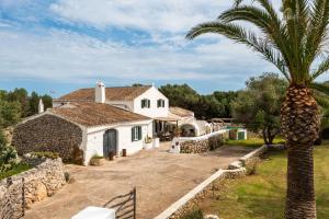 a house with a palm tree in front of it at Finca Biniparrell Vell by Escape Home in Sant Lluis