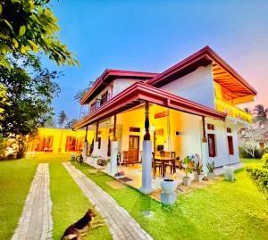 a house with a green lawn in front of it at Villa 252 Kosgoda - Beach side stay & Tours in Kosgoda