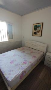 een slaapkamer met een bed met een bloemenbed bij Casa quadra mar in Arroio do Silva