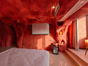 a bedroom with a red wall with a tv on it at Xinchen B&B in Ge Dao +29 photos