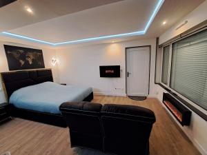 una camera da letto con un letto, un divano e una TV di La suite d'Isa a Lens