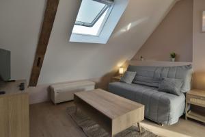 ein Wohnzimmer mit einem Sofa und einem Dachfenster in der Unterkunft Les Trois Rois 5 - Centre Avranches in Avranches